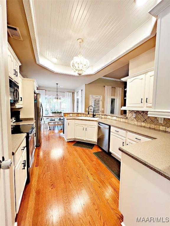 267 River Birch Cir, Wetumpka, AL 36093 - kitchen with stainless steel appliances, a chandelier, a peninsula, light wood finished floors, and white cabinetry