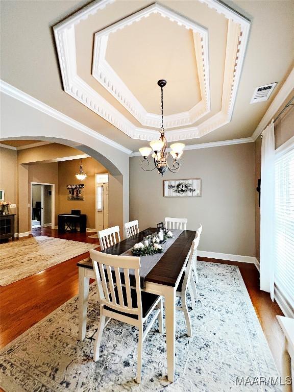 267 River Birch Cir, Wetumpka, AL 36093 - dining space with arched walkways, a chandelier, a tray ceiling, wood finished floors, and ornamental molding
