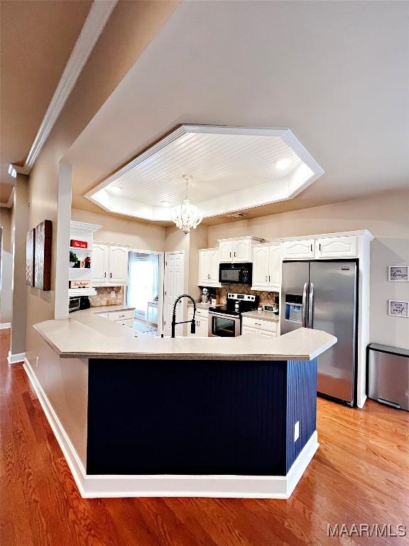 267 River Birch Cir, Wetumpka, AL 36093 - kitchen with stainless steel appliances, a tray ceiling, light wood finished floors, backsplash, and crown molding
