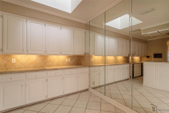 1609 Wentworth Dr, Montgomery, AL 36106 - kitchen featuring a skylight, tasteful backsplash, ornamental molding, light tile patterned flooring, and light countertops