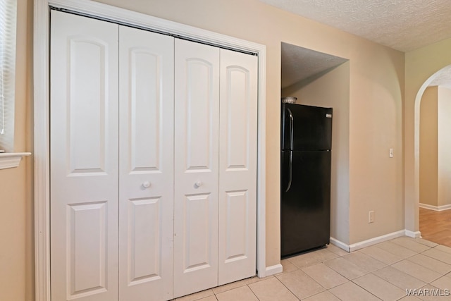 2014 Commodore St, Montgomery, AL 36106 - kitchen featuring freestanding refrigerator, arched walkways, a textured ceiling, and light tile patterned flooring