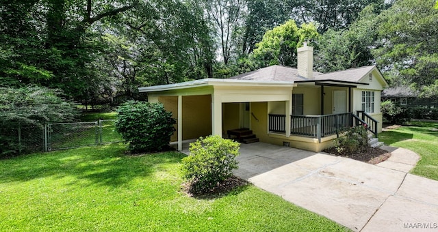 2014 Commodore St, Montgomery, AL 36106 - view of front facade featuring a gate, an attached carport, concrete driveway, a chimney, and view of wooded area