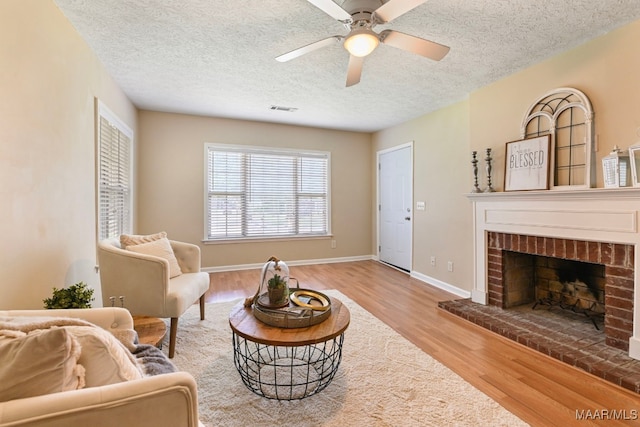 2014 Commodore St, Montgomery, AL 36106 - living area with wood finished floors, a fireplace, a ceiling fan, and a textured ceiling