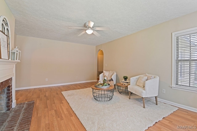 2014 Commodore St, Montgomery, AL 36106 - sitting room with arched walkways, wood finished floors, ceiling fan, a fireplace, and a textured ceiling
