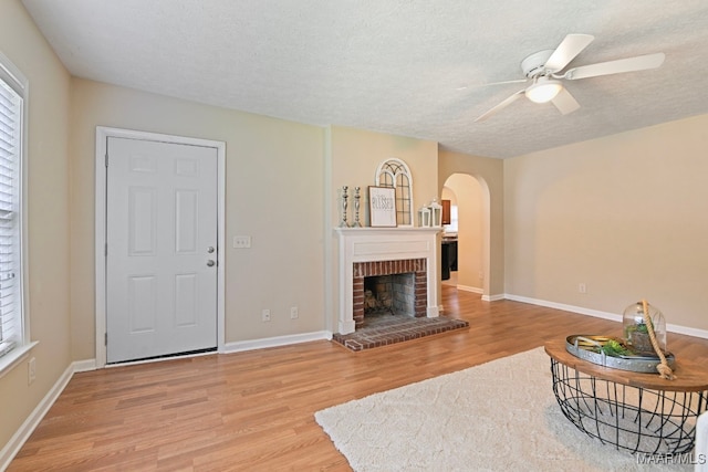 2014 Commodore St, Montgomery, AL 36106 - living area featuring arched walkways, light wood-type flooring, ceiling fan, a fireplace, and healthy amount of natural light