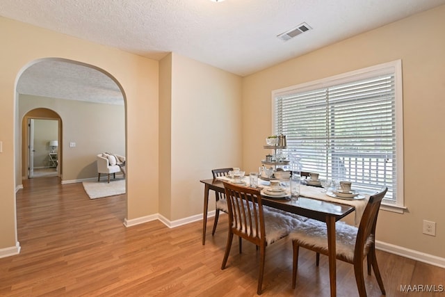 2014 Commodore St, Montgomery, AL 36106 - dining room with arched walkways, light wood-type flooring, and a textured ceiling