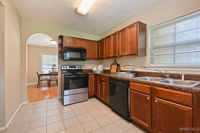 2014 Commodore St, Montgomery, AL 36106 - kitchen with black appliances, arched walkways, dark countertops, brown cabinetry, and a textured ceiling