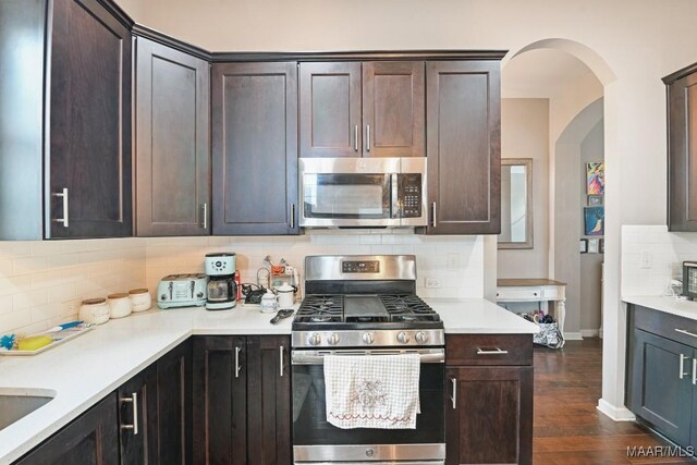 905 Overture Dr, Montgomery, AL 36117 - kitchen featuring appliances with stainless steel finishes, arched walkways, decorative backsplash, and dark brown cabinets