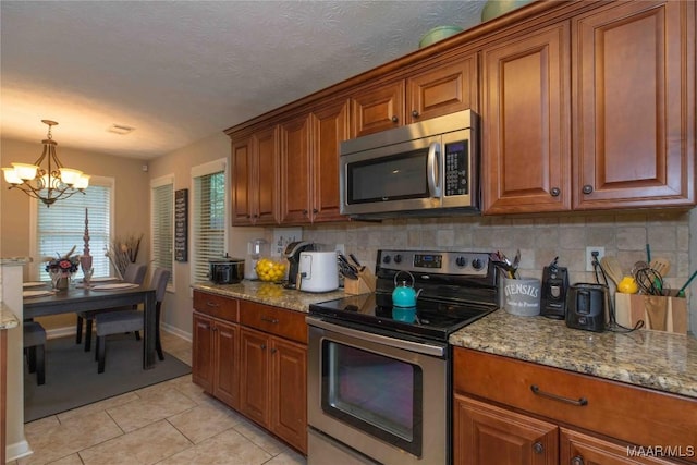 6209 Sycamore Dr, Montgomery, AL 36117 - kitchen with stainless steel appliances, brown cabinetry, and decorative backsplash