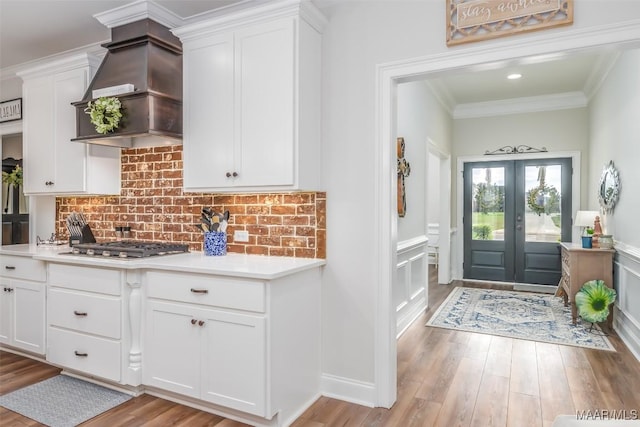 235 Midland Dr, Wetumpka, AL 36093 - kitchen with exhaust hood, light countertops, white cabinetry, tasteful backsplash, and wood finished floors