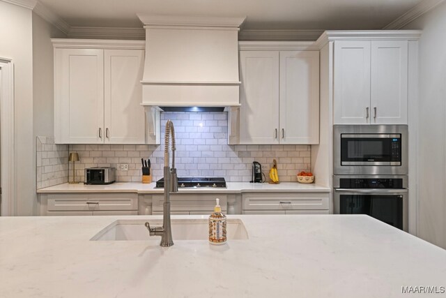 311 Alston Dr, Wetumpka, AL 36093 - kitchen with stainless steel appliances, custom range hood, white cabinetry, decorative backsplash, and crown molding