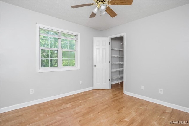 215 Hunters Rd, Eclectic, AL 36024 - unfurnished bedroom featuring light wood-style floors, a walk in closet, ceiling fan, and a textured ceiling