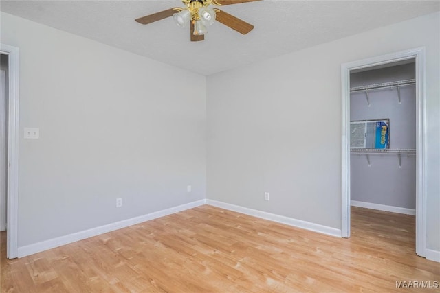 215 Hunters Rd, Eclectic, AL 36024 - unfurnished bedroom with light wood-style flooring, a walk in closet, and a ceiling fan