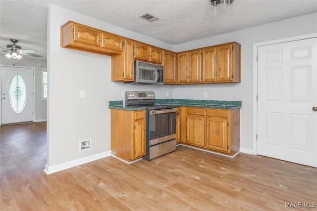215 Hunters Rd, Eclectic, AL 36024 - kitchen with stainless steel appliances, brown cabinets, light wood-style floors, and a textured ceiling