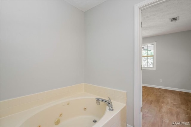 215 Hunters Rd, Eclectic, AL 36024 - full bathroom featuring a jetted tub, a textured ceiling, and wood finished floors