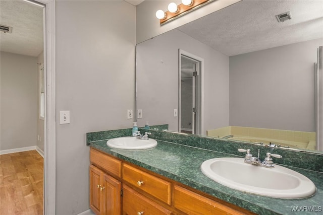 215 Hunters Rd, Eclectic, AL 36024 - full bathroom with a textured ceiling, double vanity, and wood finished floors