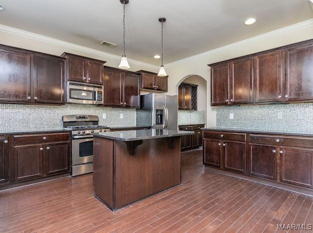 1531 Wingate Park Ct, Montgomery, AL 36117 - kitchen with appliances with stainless steel finishes, arched walkways, a kitchen island, a kitchen breakfast bar, and dark stone countertops