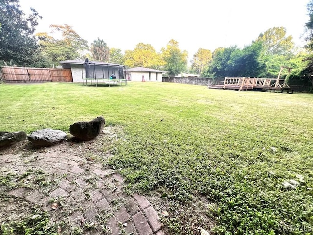 3628 Bankhead Ave, Montgomery, AL 36111 - fenced backyard featuring a trampoline, a deck, and view of scattered trees