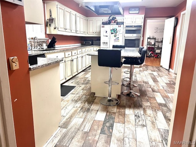 3628 Bankhead Ave, Montgomery, AL 36111 - kitchen with double oven, white refrigerator with ice dispenser, a kitchen island, light stone countertops, and light wood-style floors