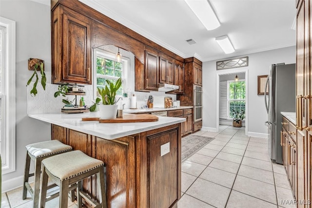 9021 Creek Side Trl, Hope Hull, AL 36043 - kitchen featuring stainless steel appliances, a peninsula, healthy amount of natural light, a kitchen bar, and crown molding
