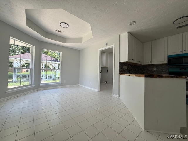 6524 Foxleigh Ct, Montgomery, AL 36116 - kitchen with black microwave, a textured ceiling, dark countertops, decorative backsplash, and a tray ceiling