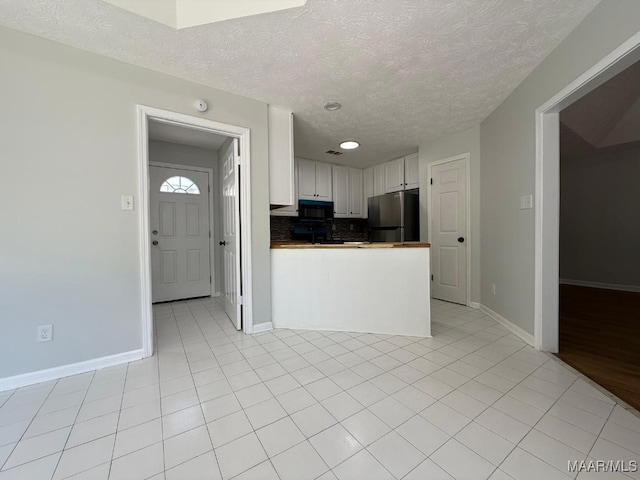 6524 Foxleigh Ct, Montgomery, AL 36116 - kitchen featuring freestanding refrigerator, black microwave, a textured ceiling, white cabinets, and a peninsula