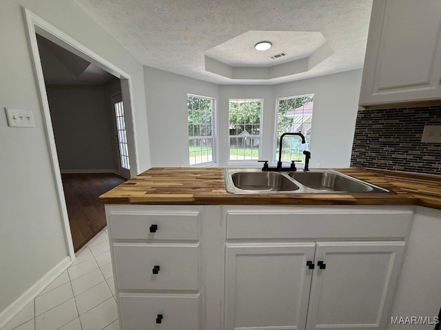 6524 Foxleigh Ct, Montgomery, AL 36116 - kitchen featuring butcher block counters, a textured ceiling, backsplash, white cabinetry, and a tray ceiling