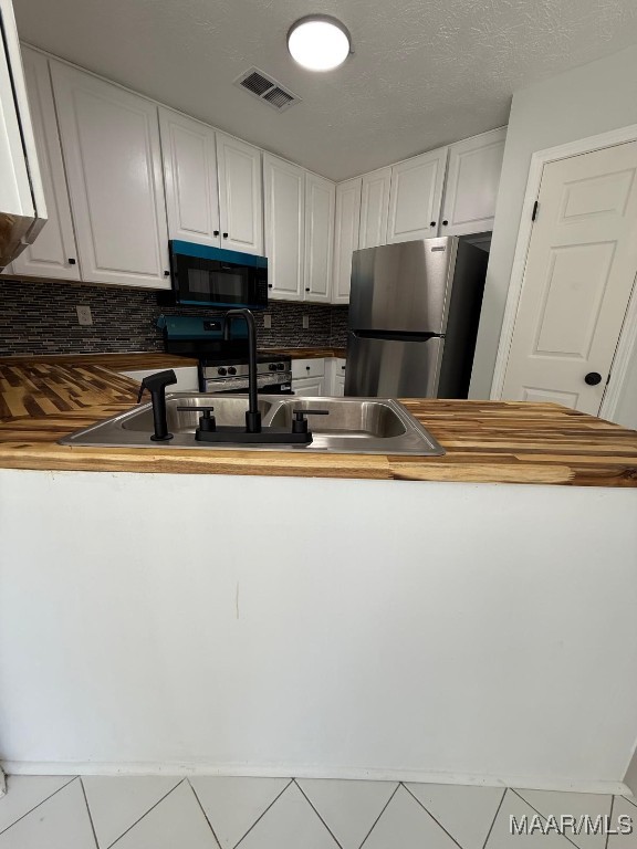 6524 Foxleigh Ct, Montgomery, AL 36116 - kitchen with stainless steel appliances, wooden counters, white cabinets, and tasteful backsplash
