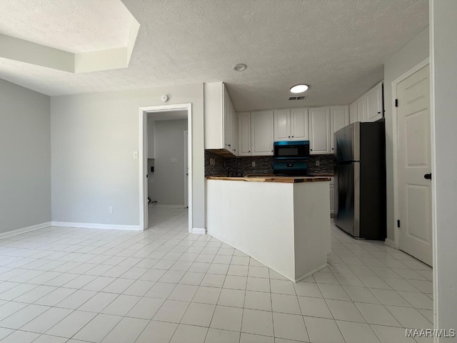 6524 Foxleigh Ct, Montgomery, AL 36116 - kitchen featuring black microwave, freestanding refrigerator, a textured ceiling, tasteful backsplash, and white cabinetry