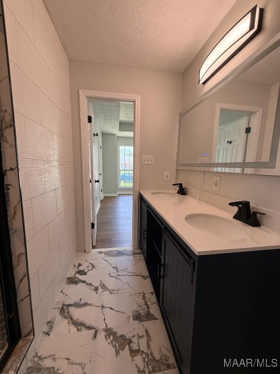 6524 Foxleigh Ct, Montgomery, AL 36116 - full bathroom featuring marble look tiles, double vanity, and a textured ceiling