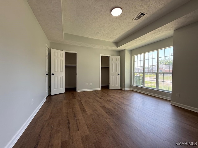 6524 Foxleigh Ct, Montgomery, AL 36116 - unfurnished bedroom featuring a textured ceiling, dark wood-style floors, a raised ceiling, and two closets