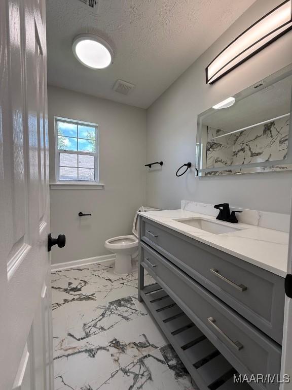 6524 Foxleigh Ct, Montgomery, AL 36116 - bathroom featuring marble look tile flooring, vanity, a textured ceiling, and a marble finish shower