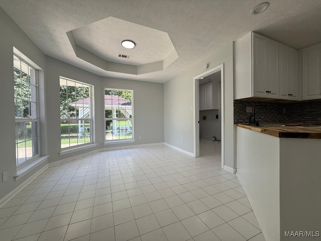 6524 Foxleigh Ct, Montgomery, AL 36116 - spare room featuring a textured ceiling, a tray ceiling, light tile patterned flooring, and healthy amount of natural light