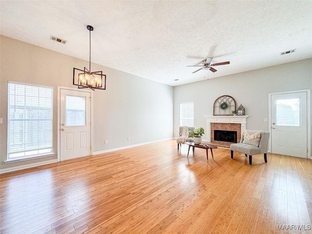 9642 Greythorne Way, Montgomery, AL 36117 - living room featuring light wood-style flooring, a fireplace, a textured ceiling, ceiling fan, and a chandelier