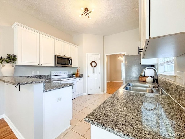 9642 Greythorne Way, Montgomery, AL 36117 - kitchen with white range with electric cooktop, stainless steel microwave, a peninsula, white cabinets, and a textured ceiling