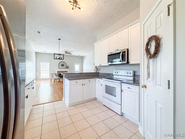 9642 Greythorne Way, Montgomery, AL 36117 - kitchen featuring appliances with stainless steel finishes, a textured ceiling, a peninsula, white cabinetry, and light tile patterned floors