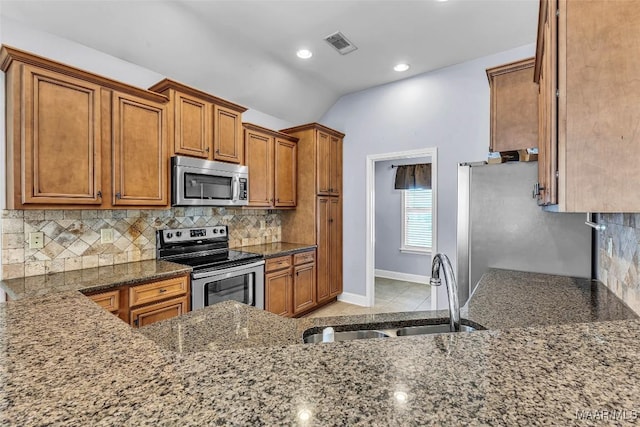 2285 Gathering Way, Prattville, AL 36066 - kitchen featuring stainless steel appliances, brown cabinetry, dark stone counters, decorative backsplash, and lofted ceiling