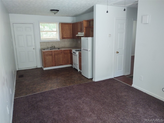 kitchen with a textured ceiling, white appliances, backsplash, dark tile floors, and sink