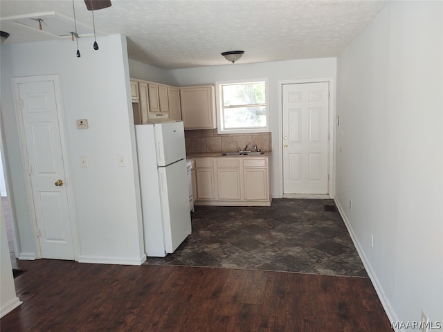 kitchen featuring white refrigerator, a textured ceiling, dark hardwood / wood-style flooring, backsplash, and sink