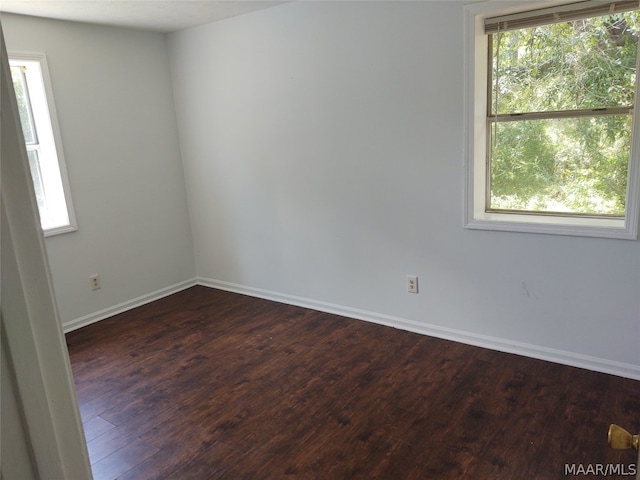 empty room with dark wood-type flooring and plenty of natural light