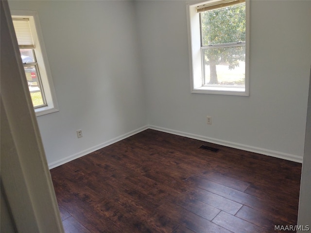 unfurnished room featuring plenty of natural light and dark hardwood / wood-style flooring