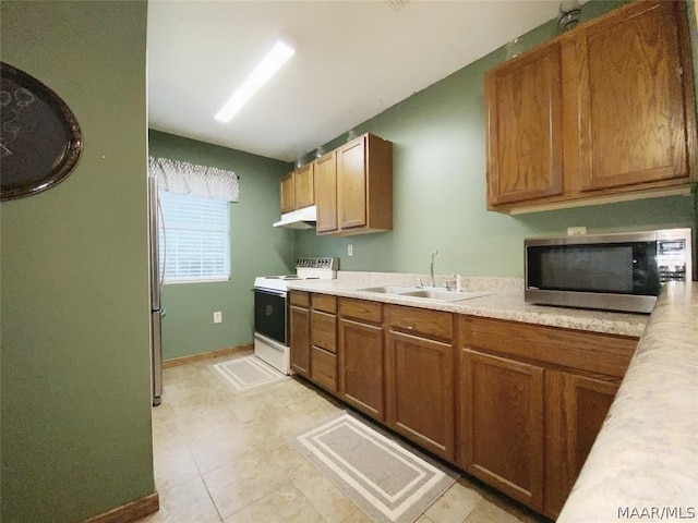 kitchen with appliances with stainless steel finishes, sink, and light tile floors