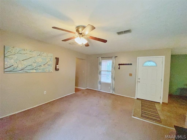 foyer entrance featuring ceiling fan and light carpet