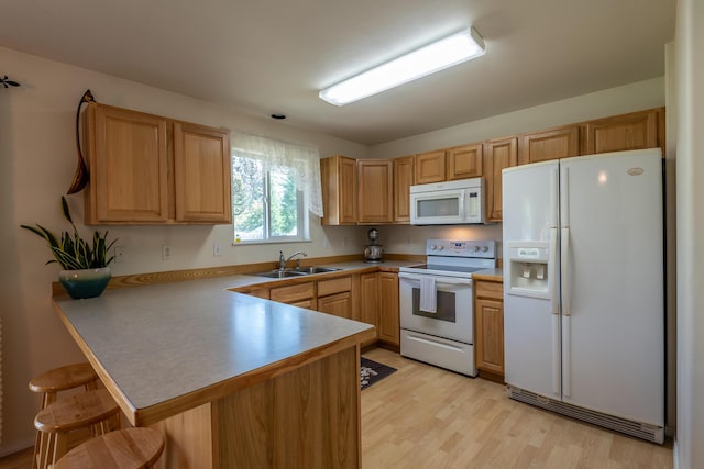 772 Cedar St, Whitefish, MT 59937 - kitchen featuring white appliances, a peninsula, a sink, a breakfast bar, and light wood finished floors