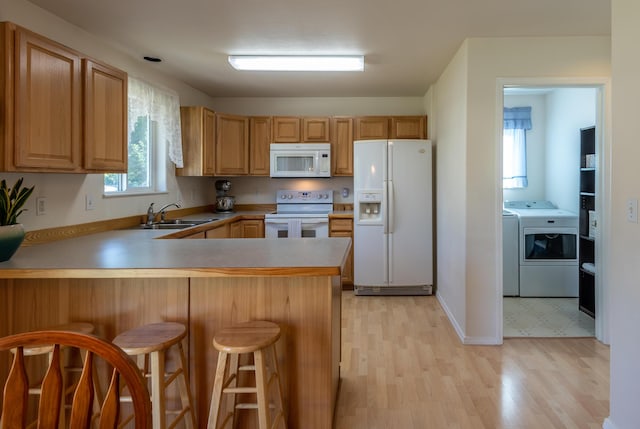 772 Cedar St, Whitefish, MT 59937 - kitchen with white appliances, a sink, separate washer and dryer, a peninsula, and light wood-type flooring