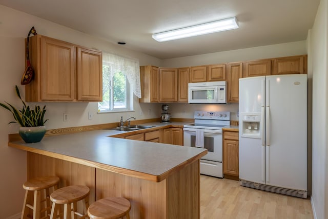 772 Cedar St, Whitefish, MT 59937 - kitchen featuring white appliances, a sink, a peninsula, a kitchen breakfast bar, and light wood-style flooring