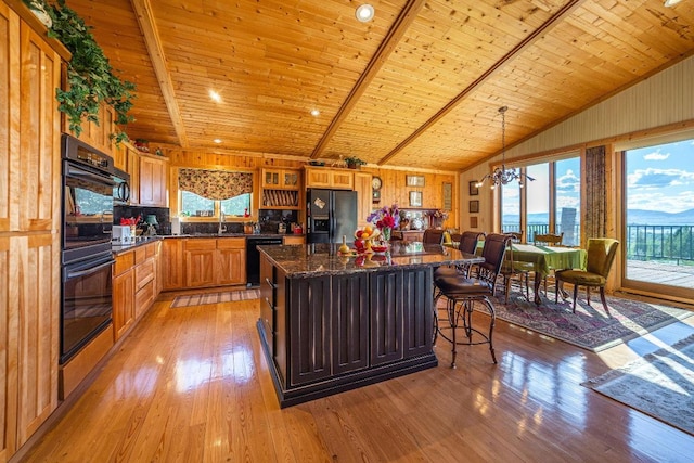 kitchen with light wood-type flooring, a center island, a kitchen breakfast bar, wooden ceiling, and black appliances