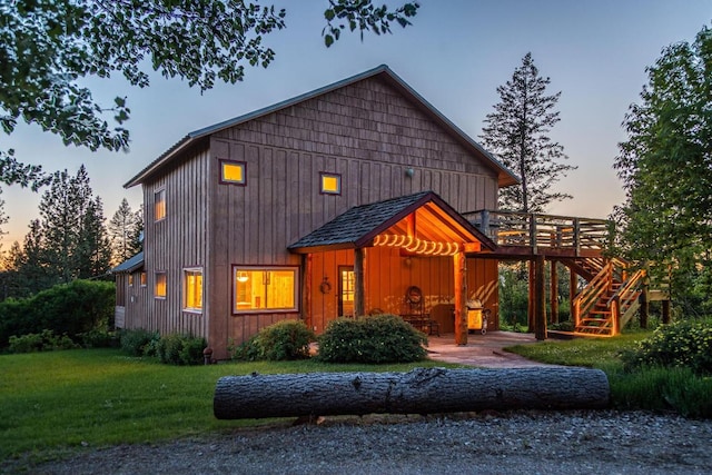 back house at dusk with a lawn and a deck