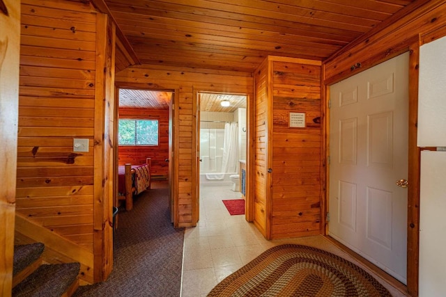 hall with wooden walls, wood ceiling, and light tile flooring