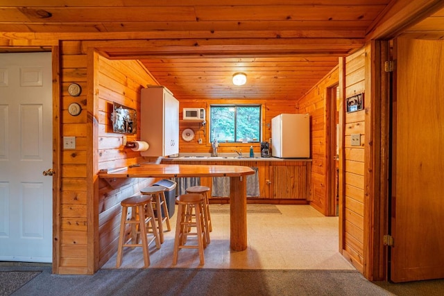 kitchen featuring light colored carpet, sink, white refrigerator, wood ceiling, and wood walls